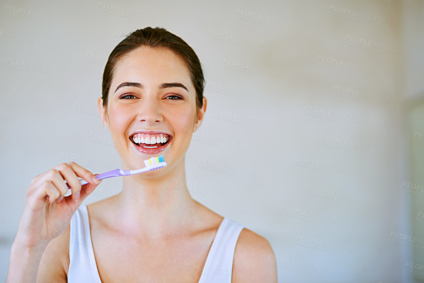 Buy stock photo Cropped shot of a young woman brushing her teeth in the bathroom