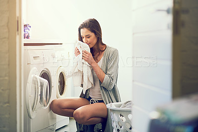 Buy stock photo Cropped shot of a young woman smelling her freshly washed towels