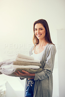 Buy stock photo Cropped shot of a young woman holding a pile of clean towels