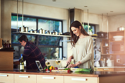 Buy stock photo Cropped shot of a young woman preparing a meal with her boyfriend in the background at home