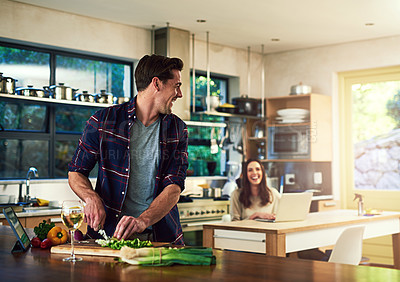 Buy stock photo Cropped shot of a young man preparing a meal with his girlfriend in the background at home