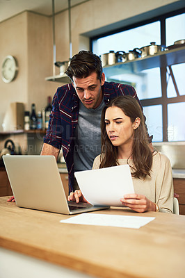 Buy stock photo Cropped shot of a young couple using a laptop while going through paperwork together at home