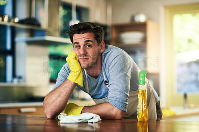 Buy stock photo Portrait of a young man looking bored while cleaning in a kitchen