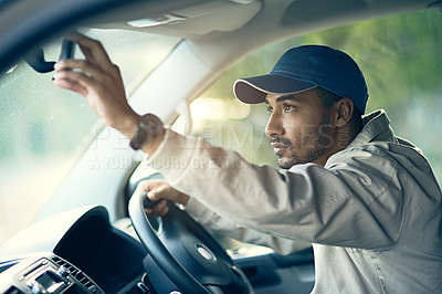 Buy stock photo Cropped shot of a delivery man adjusting the rear-view mirror of his van