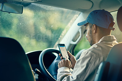 Buy stock photo Cropped shot of a delivery man using a cellphone while sitting in his van