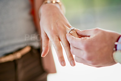Buy stock photo Closeup shot of a man putting an engagement ring onto his fiancee’s finger