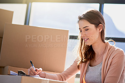 Buy stock photo Cropped shot of a young woman making notes while moving house