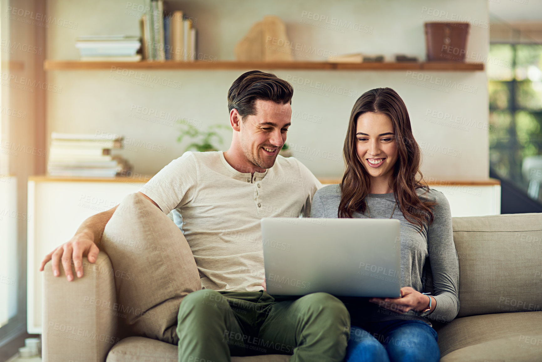 Buy stock photo Shot of a happy young couple using a laptop together on the sofa at home