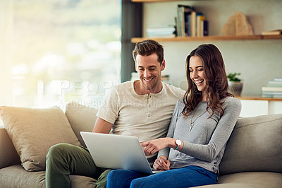 Buy stock photo Shot of a happy young couple using a laptop together on the sofa at home