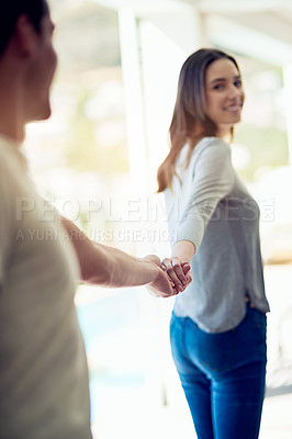 Buy stock photo Shot of a young woman holding her boyfriend’s hand and leading the way