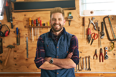 Buy stock photo Portrait of a handsome young handyman standing with his arms folded in a workshop
