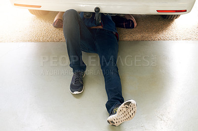 Buy stock photo High angle shot of an unrecognizable man working under his car