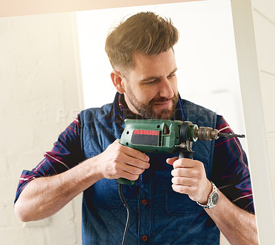 Buy stock photo Shot of a handsome young handyman using an electric drill for some DIY