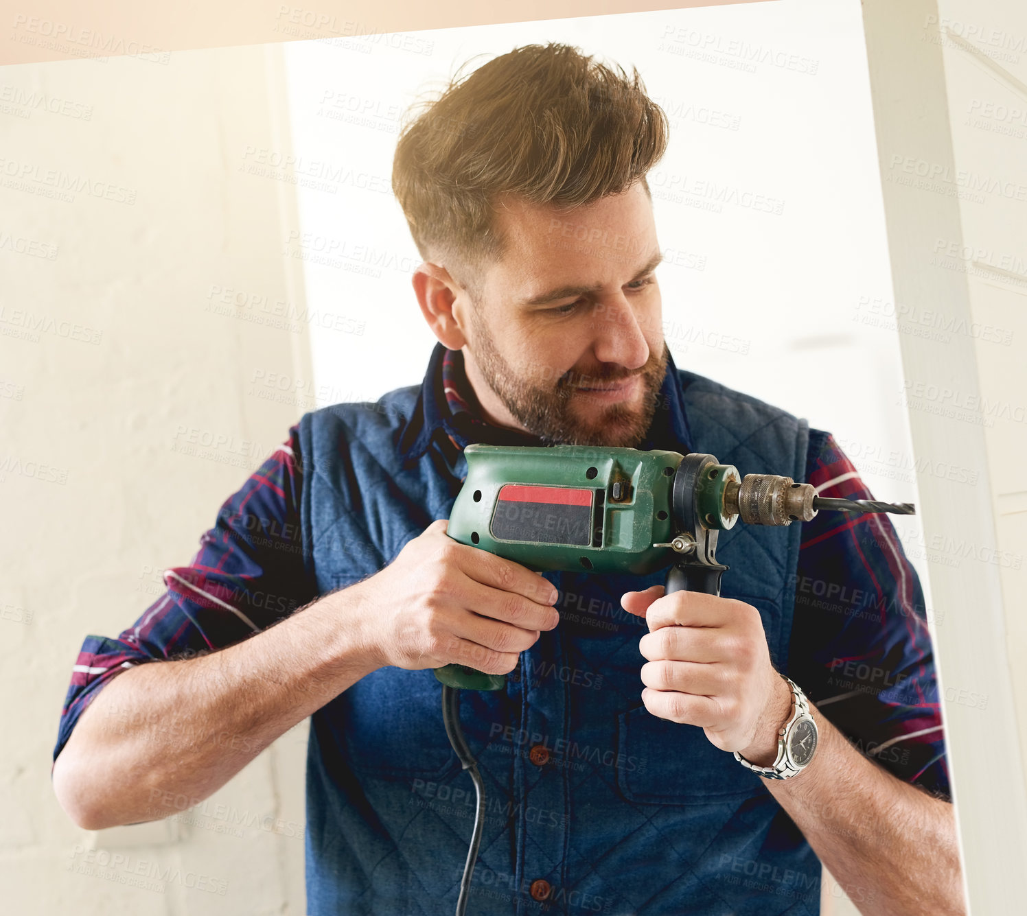 Buy stock photo Shot of a handsome young handyman using an electric drill for some DIY