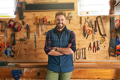 Buy stock photo Portrait of a handsome young handyman standing with his arms folded in a workshop