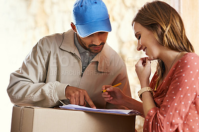 Buy stock photo Cropped shot of an attractive young woman signing for her delivery