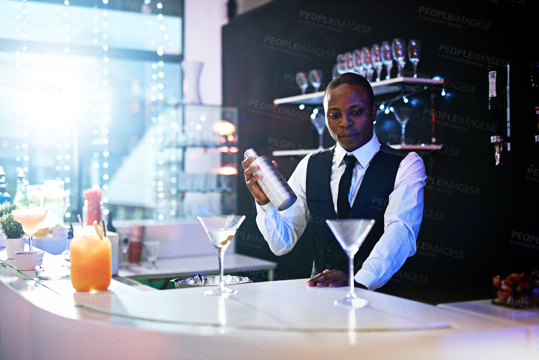 Buy stock photo Black man, bartender and shake to prepare drink in restaurant, hospitality and counter server for alcohol. Male person, mix cocktail and martini at hotel bar, waiter confidence and barman selection
