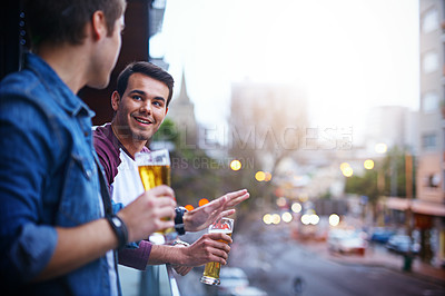 Buy stock photo Cropped shot of two guys drinking beer while standing on the balcony at a party