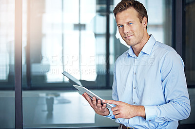 Buy stock photo Portrait of a well dressed businessman using a tablet while standing in the office