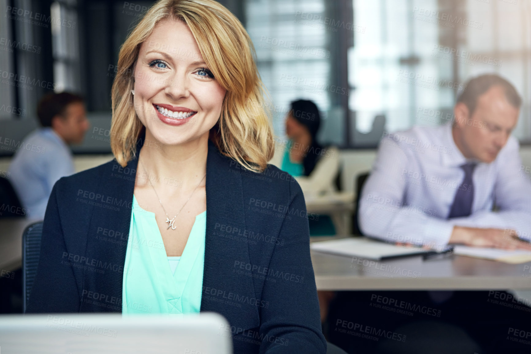 Buy stock photo Portrait of a businesswoman using a laptop at her desk with her colleagues in the background