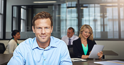 Buy stock photo Portrait of a businessman working at his desk with his colleagues in the background