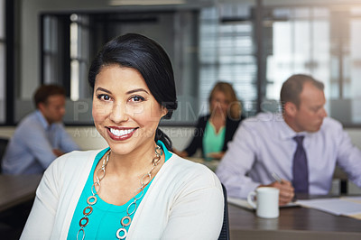 Buy stock photo Portrait of a businesswoman working at her desk with her colleagues in the background