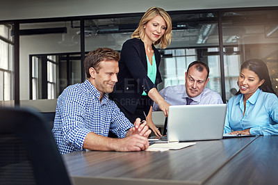 Buy stock photo Shot of a group of colleagues using a laptop together during a meeting at work