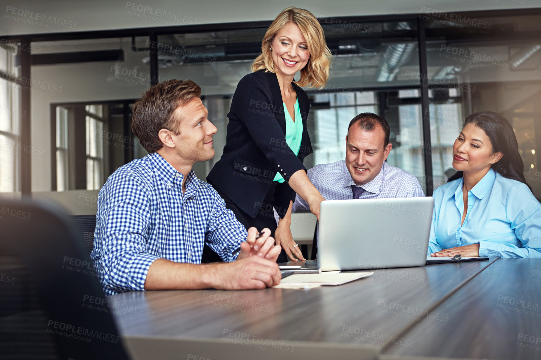 Buy stock photo Shot of a group of colleagues using a laptop together during a meeting at work