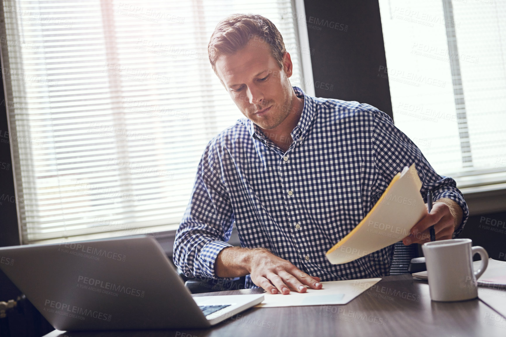 Buy stock photo Shot of a busy businessman using his laptop in the office