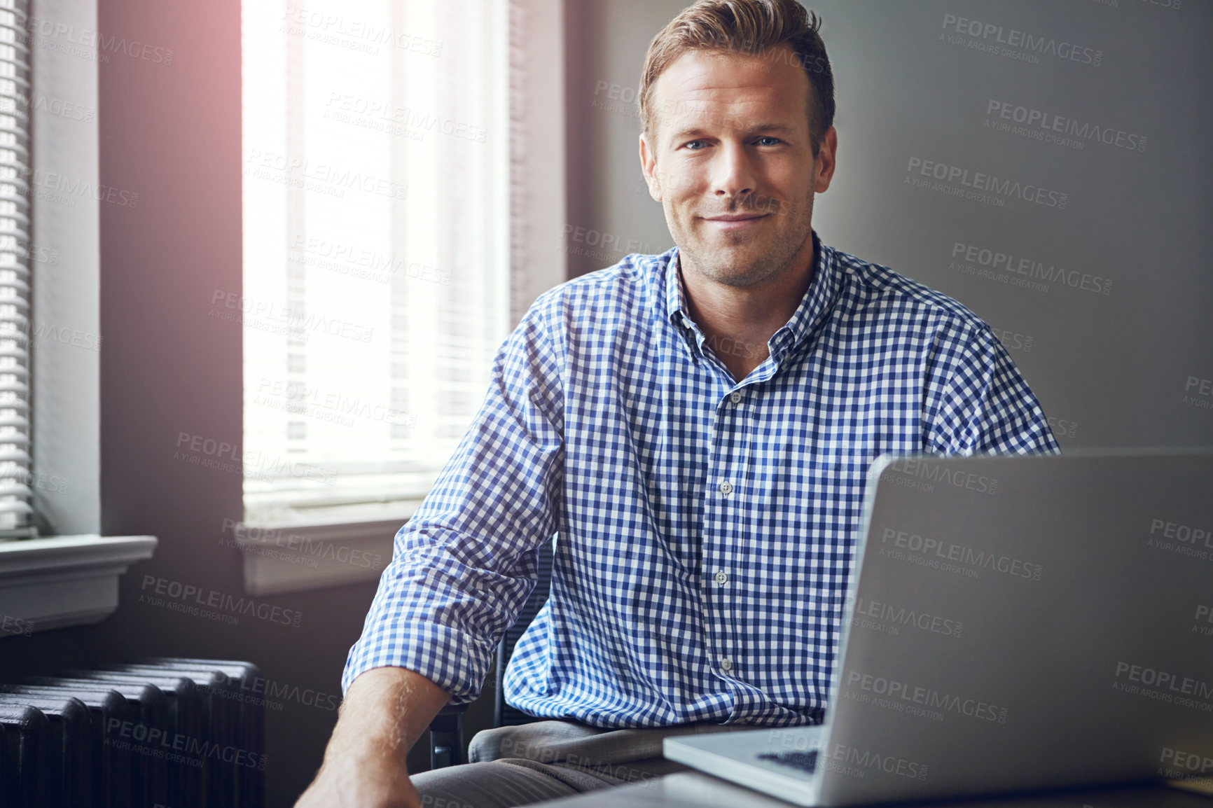 Buy stock photo Portrait of a happy businessman using his laptop in the office