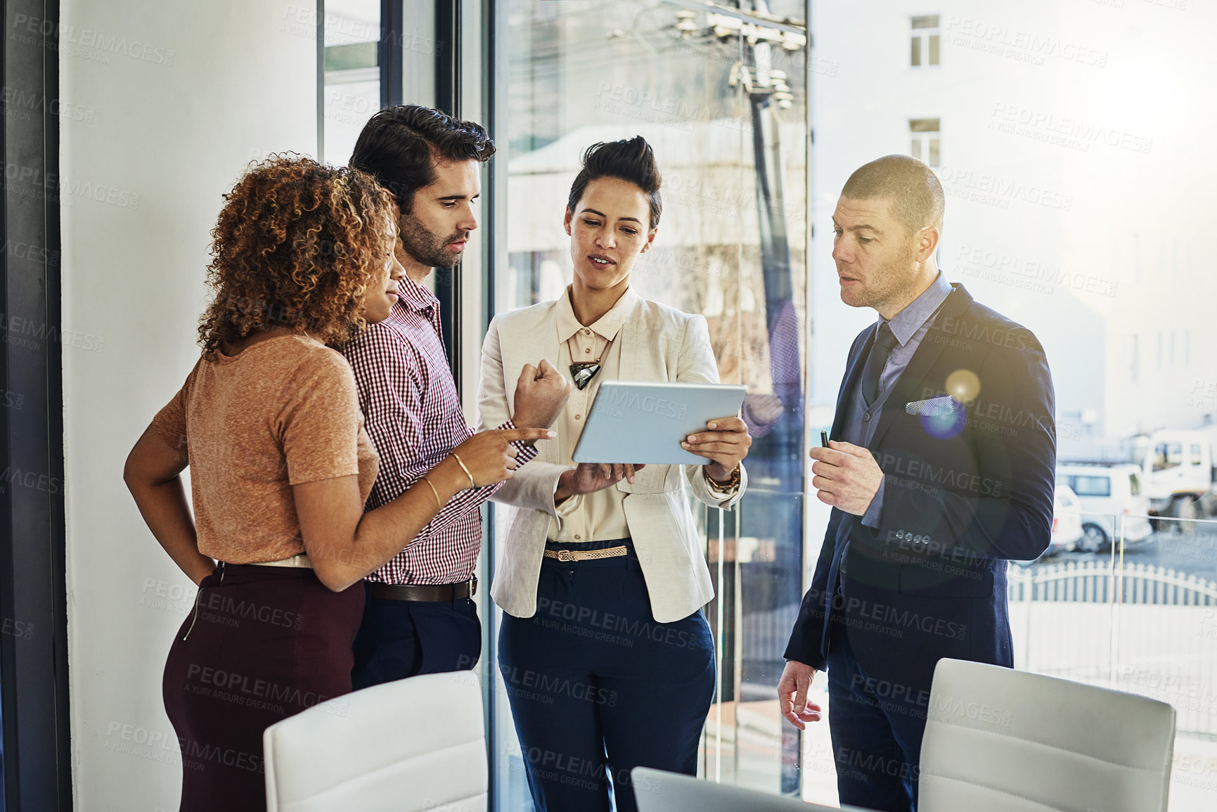 Buy stock photo Shot of a group of colleagues using a tablet while meeting in the boardroom