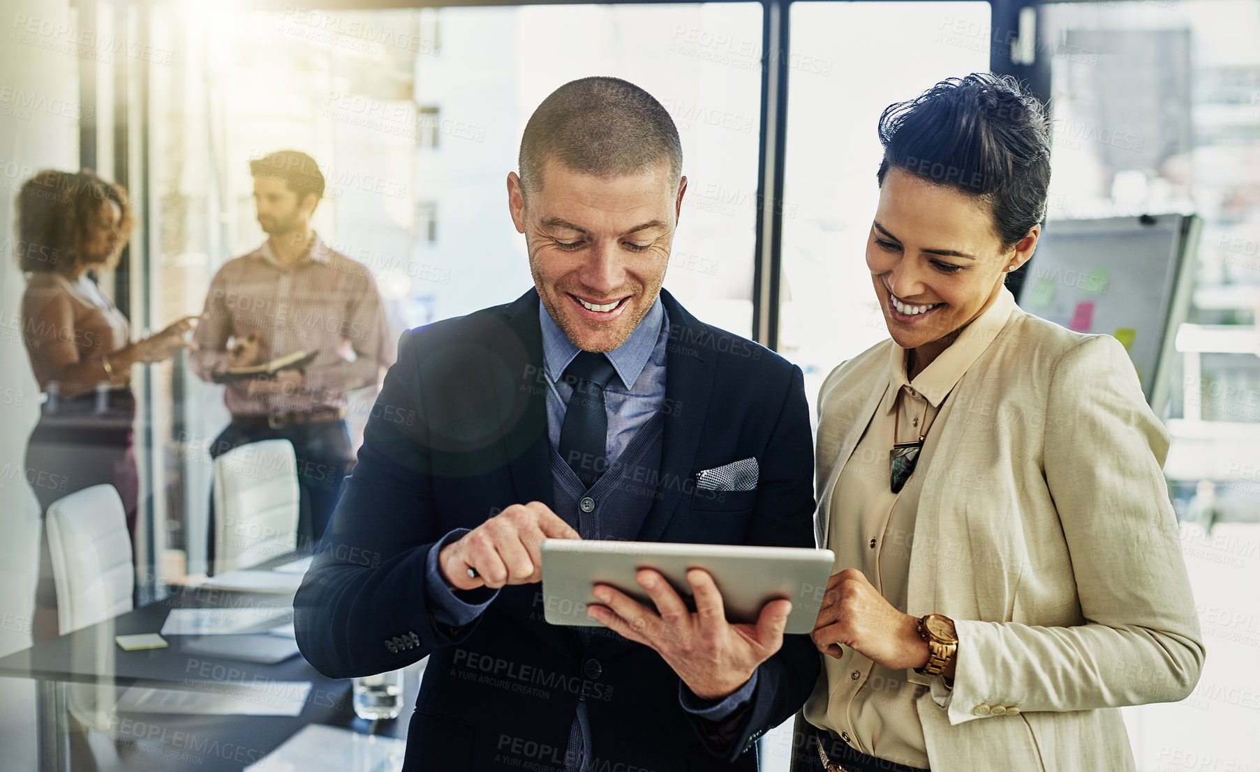 Buy stock photo Shot of two colleagues using a tablet while talking outside of the boardroom