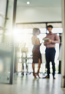Buy stock photo Shot of two colleagues using a tablet while talking outside of the boardroom