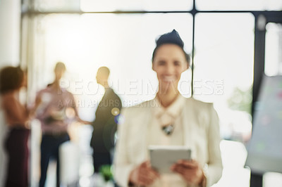 Buy stock photo Portrait of a businesswoman using her tablet while some colleagues talk in the background