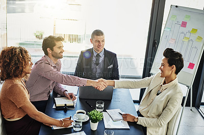 Buy stock photo Shot of two colleagues shaking hands during a meeting in the boardroom
