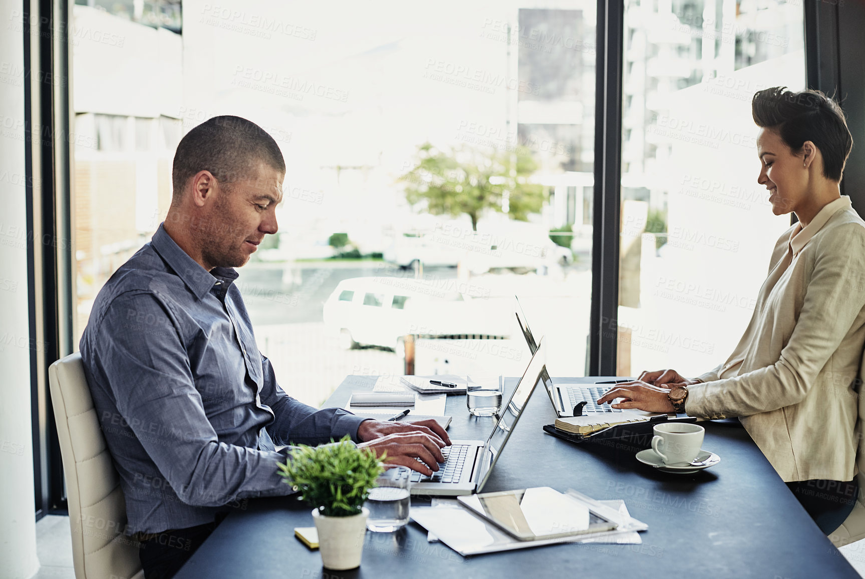 Buy stock photo Shot of two colleagues working in their office