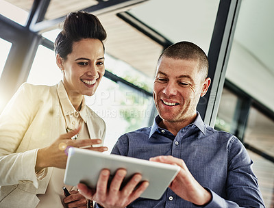 Buy stock photo Shot of two colleagues using a tablet while meeting in their office