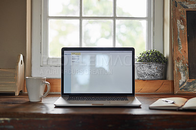 Buy stock photo Shot of a table at home with a laptop, notebook and pen