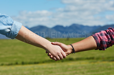 Buy stock photo Cropped shot of two unidentifiable people holding hands while standing in a grassy field