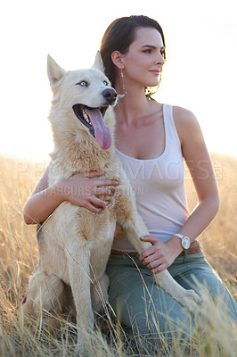 Buy stock photo Shot of an attractive young woman bonding with her dog outdoors