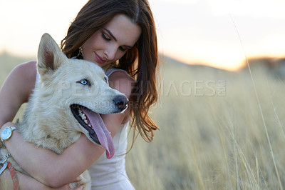 Buy stock photo Shot of an attractive young woman bonding with her dog outdoors