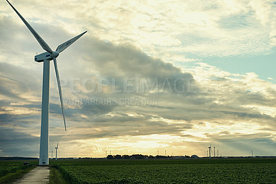 Buy stock photo Shot of a cluster of wind turbines standing in an open field