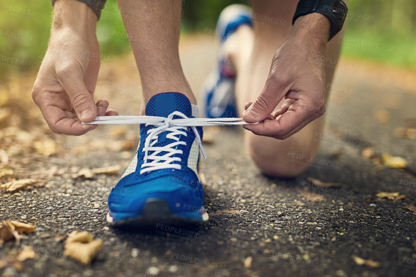 Buy stock photo Cropped shot of an unidentifiable man tying his shoes while out for a run