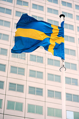 Buy stock photo Sweden, flag and building in city with wind blowing for patriotic, heritage and national pride for identity or scandinavian. Blue, yellow and emblem outdoor hanging for country and Swedish culture.