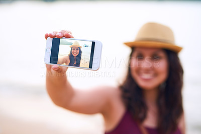 Buy stock photo Cropped shot of an attractive young woman taking selfies at the beach