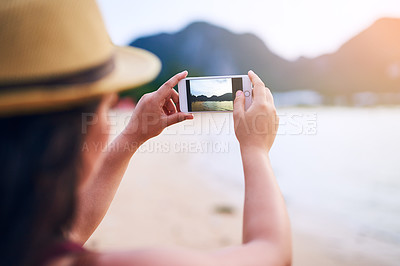 Buy stock photo Rearview shot of a young woman taking photographs at the beach