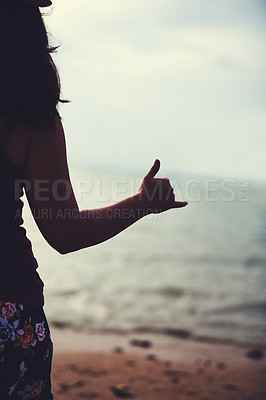 Buy stock photo Rearview shot of a young woman at the beach gesturing hang ten