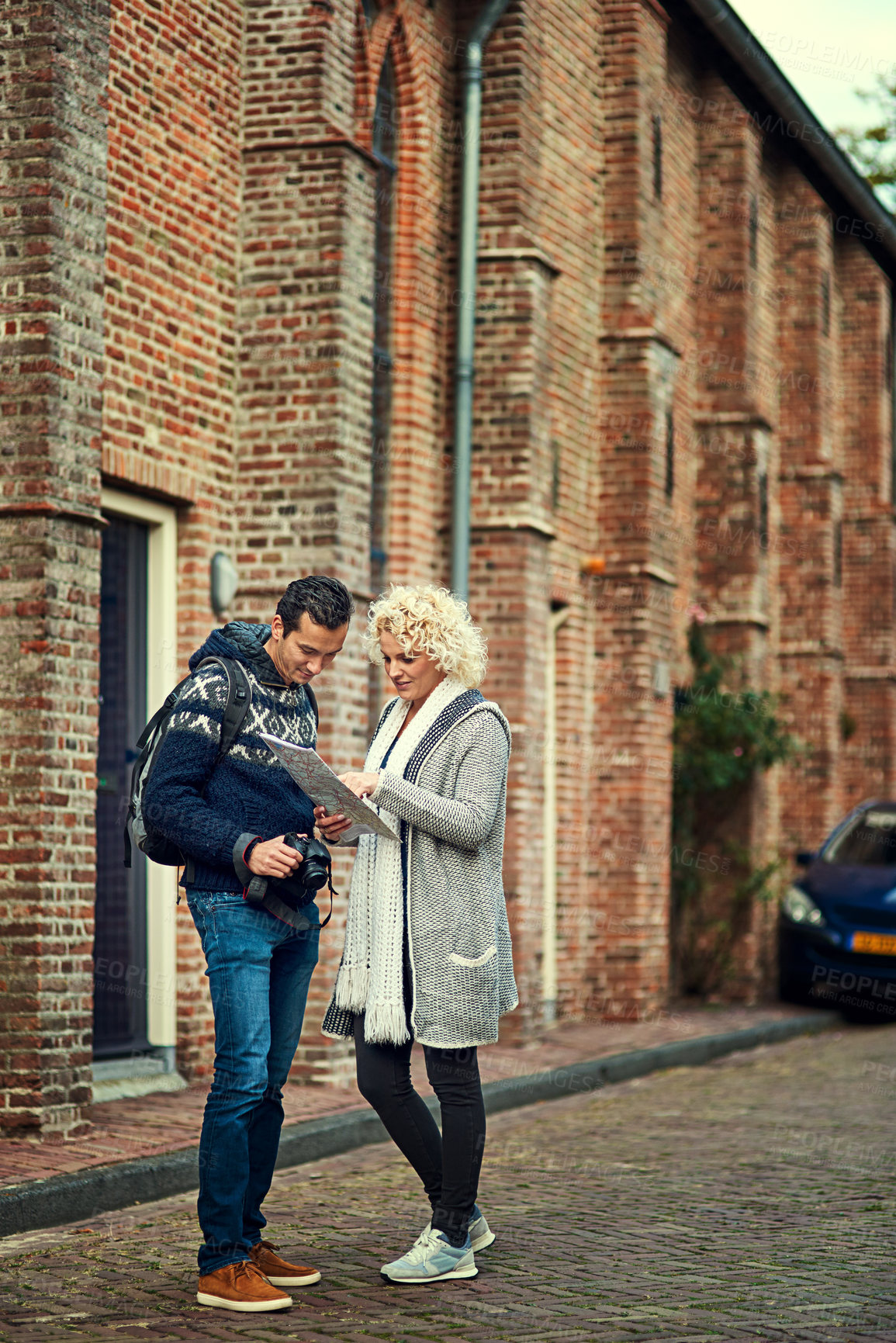 Buy stock photo Full length shot of a young couple looking at a map while on vacation