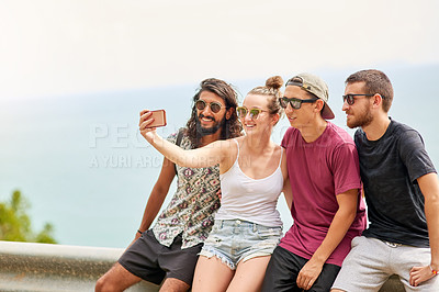 Buy stock photo Shot of a group of friends posing for a selfie while relaxing together outside