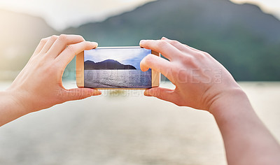 Buy stock photo Shot of an unidentifiable woman taking a picture with her smartphone while walking on the beach